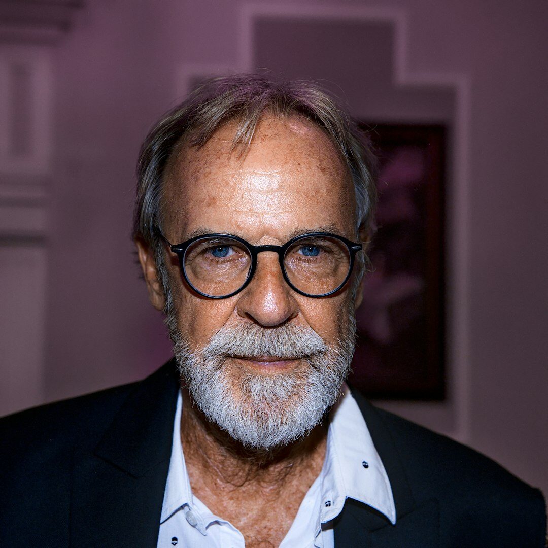 Studio portrait of a bearded man with glasses, founder and director